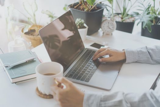 Woman is working on clean nature workspace at home with laptop, planner notebook and calculator. Business finance office concept.