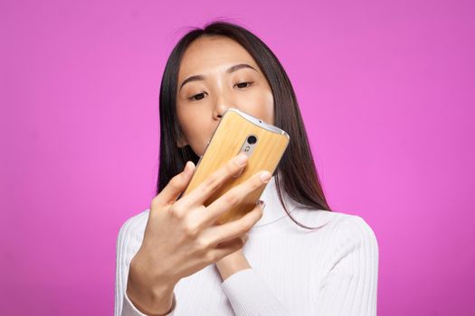 asian woman looking at phone internet technology pink background. High quality photo