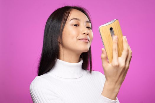 pretty woman in white sweater phone in hands pink background fashion communication. High quality photo