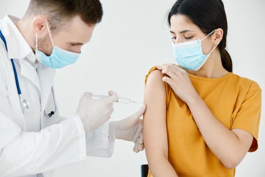 doctor in medical mask injecting a woman's shoulder vaccination injection health. High quality photo