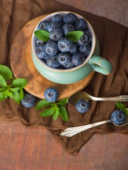 Fresh blueberry in a cup with leaves of mint.