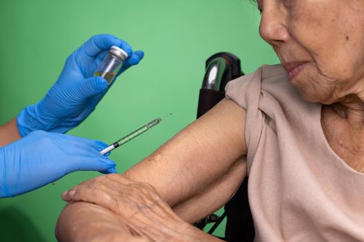 Chroma key, nurse doing vaccine injection to senior woman.