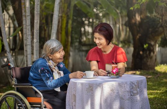 Senior woman relaxing with daughter  in backyard.