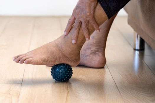 Elderly woman doing rubber ball for exercise fingers, palm ,hand and foot muscle with caregiver take care.