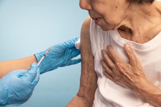 Closeup nurse doing vaccine injection to senior woman.