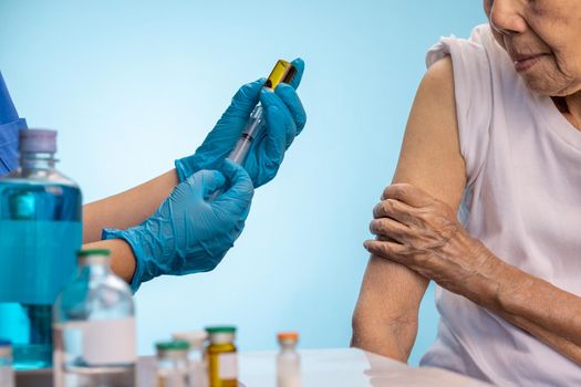 Closeup nurse doing vaccine injection to senior woman.