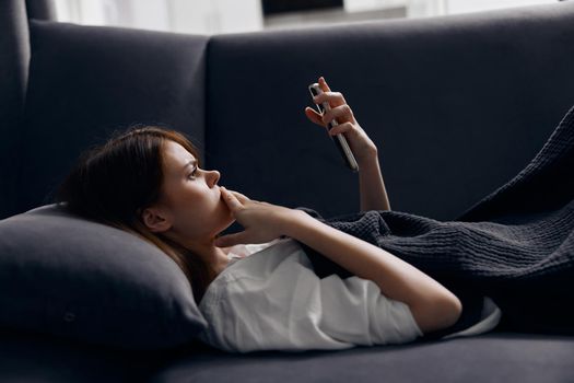 woman on sofa looking at mobile phone screen and soft pillow. High quality photo