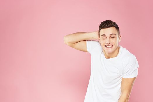 Emotional man gesturing with his hands white t-shirt pink isolated background. High quality photo