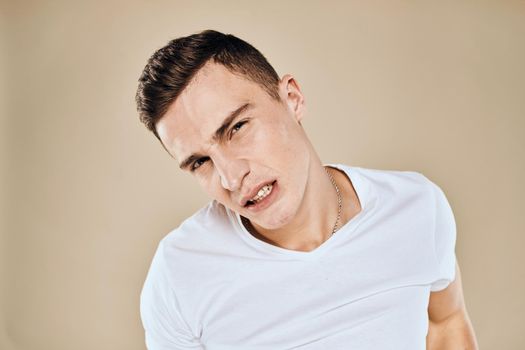 Man with displeased facial expression emotions white t-shirt gestures with hands beige background. High quality photo