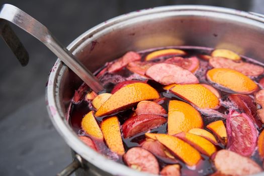 closeup of mulled wine, preparing in big old metal kettle on fire, above view, Traditional Christmas fair market beverage