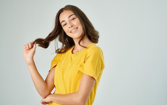 pretty brunette in a yellow t-shirt gray background smile emotions. High quality photo