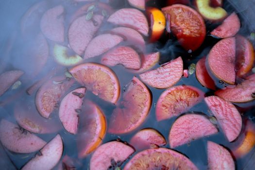 closeup of mulled wine, preparing in big old metal kettle on fire, above view, Traditional Christmas fair market beverage