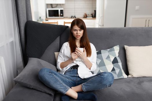a woman with a phone in her hands a serious look resting at home in an apartment. High quality photo