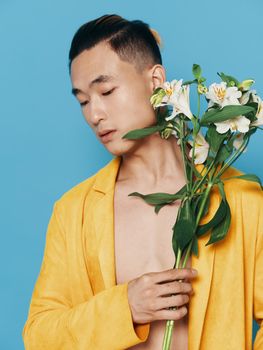A guy of Asian appearance with a bouquet of flowers portrait yellow coat synthetic winterizer Asian appearance. High quality photo