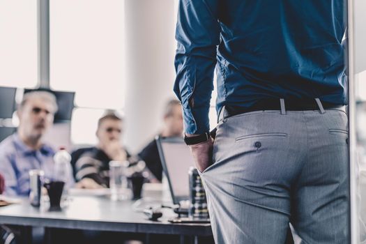 Business man making a presentation at office. Business executive delivering a presentation to his colleagues during meeting or in-house business training. Rear view. Business and entrepreneurship.