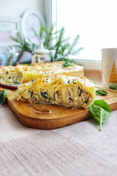 A large piece of baked lasagna on a wooden chopping board in close-up.Texture or background