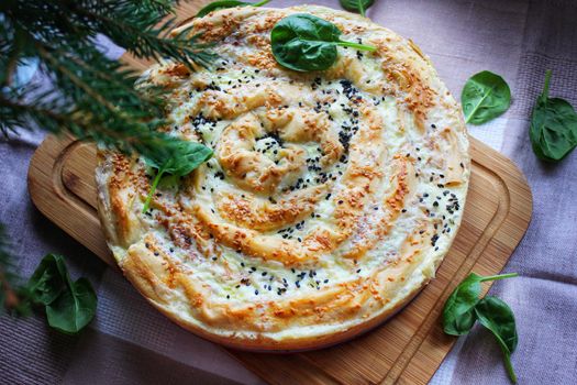Homemade baked lasagna with a crispy crust on a wooden cutting board and decorated with herbs