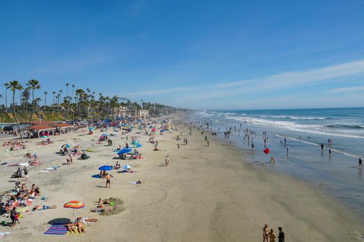 People on the beach enjoying beautiful summer day at Oceanside beach in San Diego, California. 