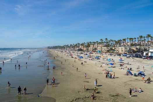 People on the beach enjoying beautiful summer day at Oceanside beach in San Diego, California. 