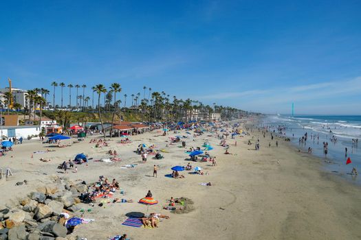 People on the beach enjoying beautiful summer day at Oceanside beach in San Diego, California. 