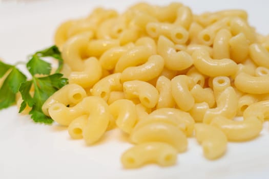 Boiled yellow pasta on a white plate. Close-up.