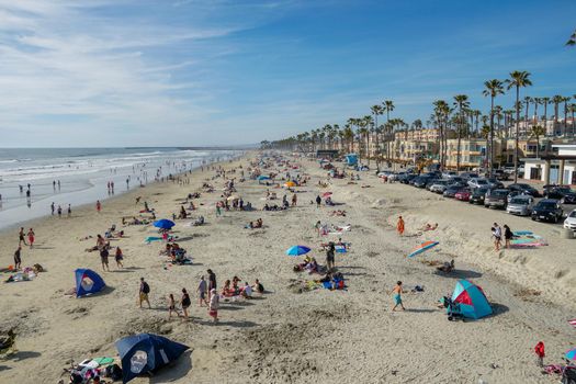 People on the beach enjoying beautiful summer day at Oceanside beach in San Diego, California. 