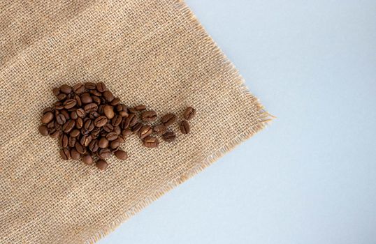 Coffee beans and burlap lie on a gray background.