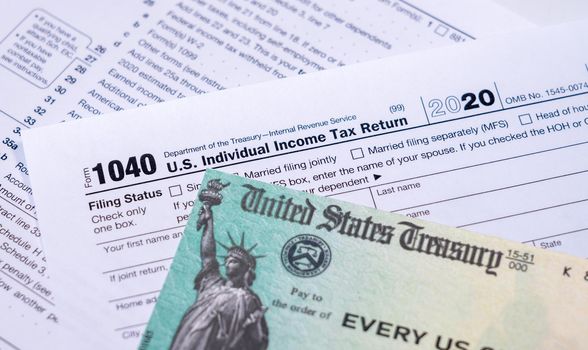 US Treasury stimulus check laying on a form 1040 tax return for 2020 to illustrate questions about qualification for payment