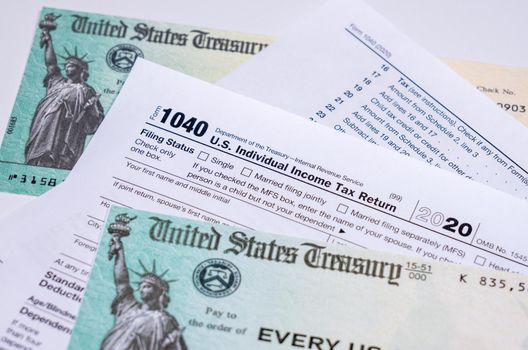 US Treasury stimulus check laying on a form 1040 tax return for 2020 to illustrate questions about qualification for payment