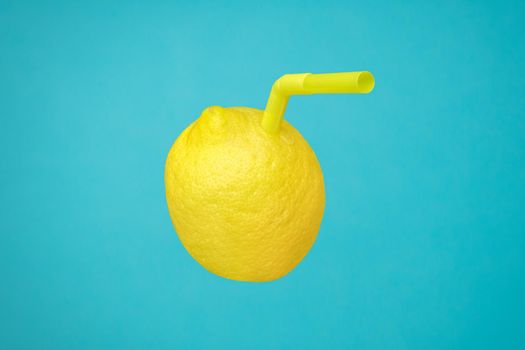 Vitamin C in yellow lemon fruit minimal concept or homemade lemonade squeezed refreshing drink. Ripe juicy lemon as a drink in glass with straw or natural freshly lemonade made with real fruit on blue