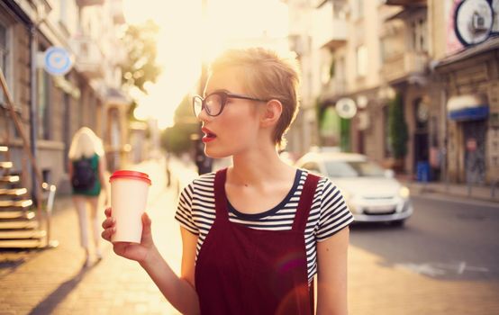 pretty woman with short hair and red lips on the street walk glass with drink. High quality photo