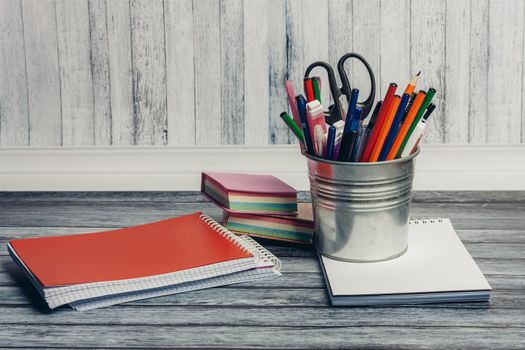 stationery in an iron jar and notepads on a wooden table in the office. High quality photo
