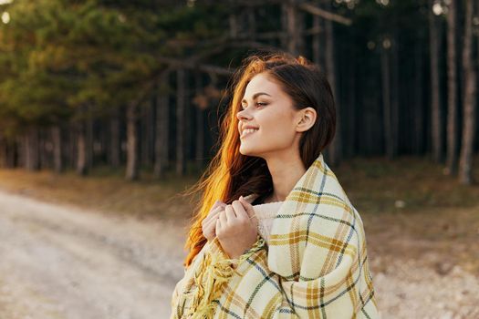 Happily and traveler on the road near the trees with a blanket on her shoulders. High quality photo
