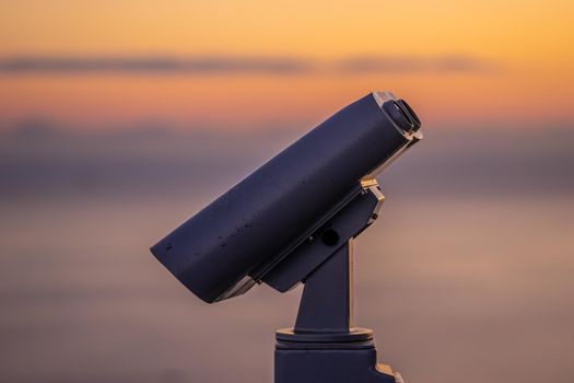 Binoculars for tourists on the background of the sunset sky.