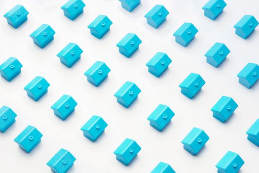 Abstract model village or city district construction new neighborhood pattern of many blue miniature small toy houses stand a rows on white minimal design. Real estate or property market cottage home