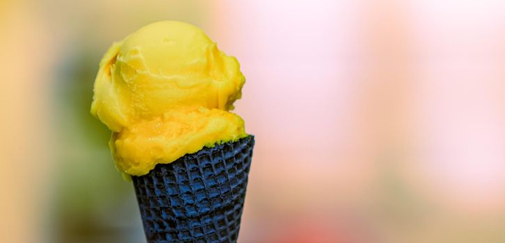 yellow ice cream in a wafer chocolate cone.