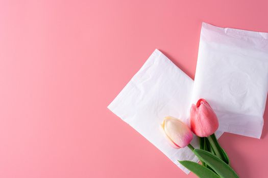 Sanitary pad, Sanitary napkin with tulip flower on pink background. Menstruation, Feminine hygiene, top view.