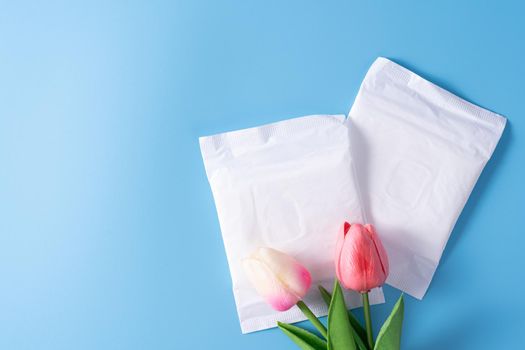 Sanitary pad, Sanitary napkin with tulip flower on blue background. Menstruation, Feminine hygiene, top view.