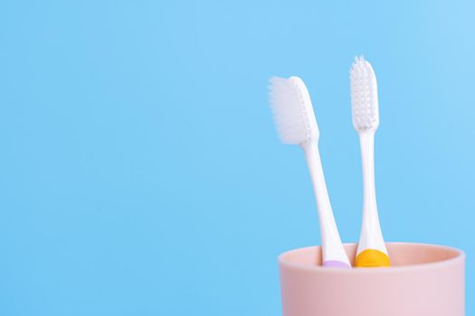 Closeup toothbrush in the glass isolated blue background. Copy space for text.