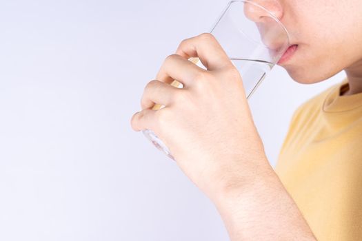 Man drinking water isolated grey background. Clean drinking water in clear glass.