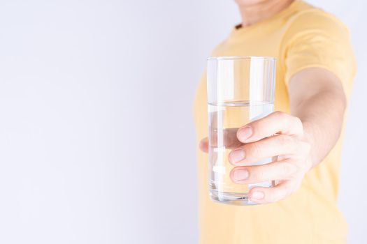 Man holding glass of water isolated grey background. Clean drinking water in clear glass.