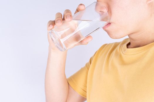 Man drinking water isolated grey background. Clean drinking water in clear glass.