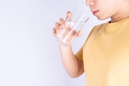 Man drinking water isolated grey background. Clean drinking water in clear glass.