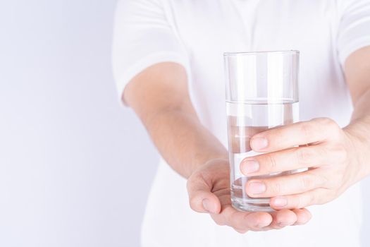 Man holding glass of water isolated grey background. Clean drinking water in clear glass.