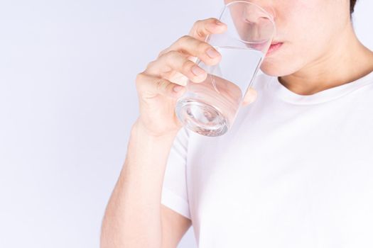 Man drinking water isolated grey background. Clean drinking water in clear glass.
