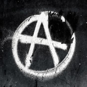 Sprayed anarchy symbol with overspray on grungy wall