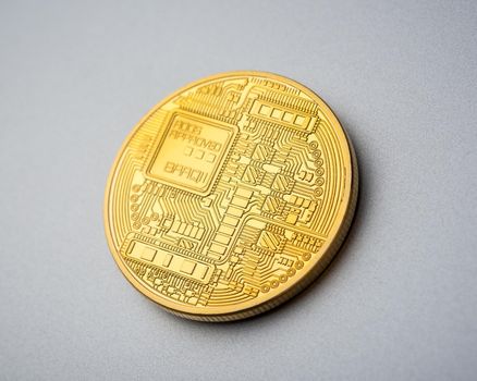 Back side of physical golden cryptocurrency Bitcoin coin on brushed aluminium background.
