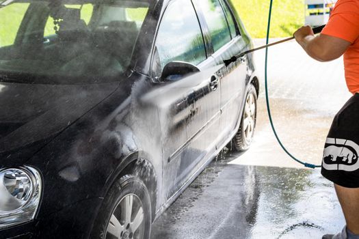 Washing and cleaning car in self service car wash station. Car washing using high pressure water in Bucharest, Romania, 2021