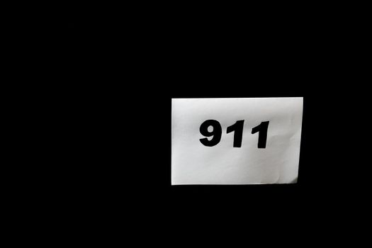 Call 911 and emergency call concept, text 911 on paper isolated on black.