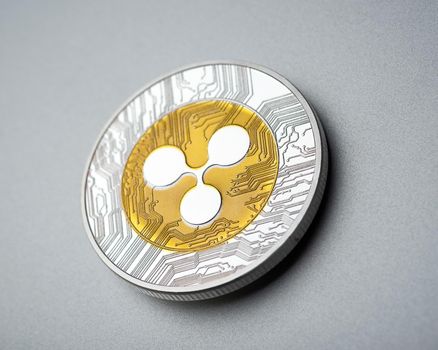Physical cryptocurrency Ripple coin on brushed aluminium background.